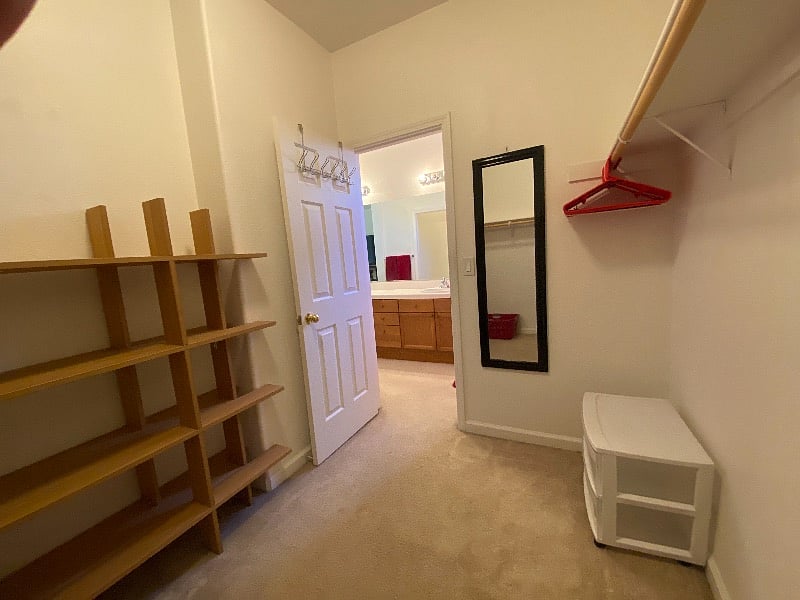 Master bedroom walk-in closet. Spacious with shelves, hanging rods, laundry basket, and mirror.