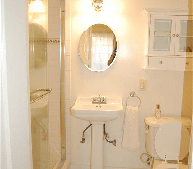 Bathroom with shower, sink, toilet and storage. White subway tile and hand finished Provencal tile runner.