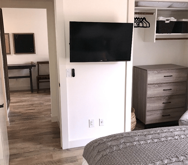Master bedroom with queen sized bed, drawer, aditional chair & TV