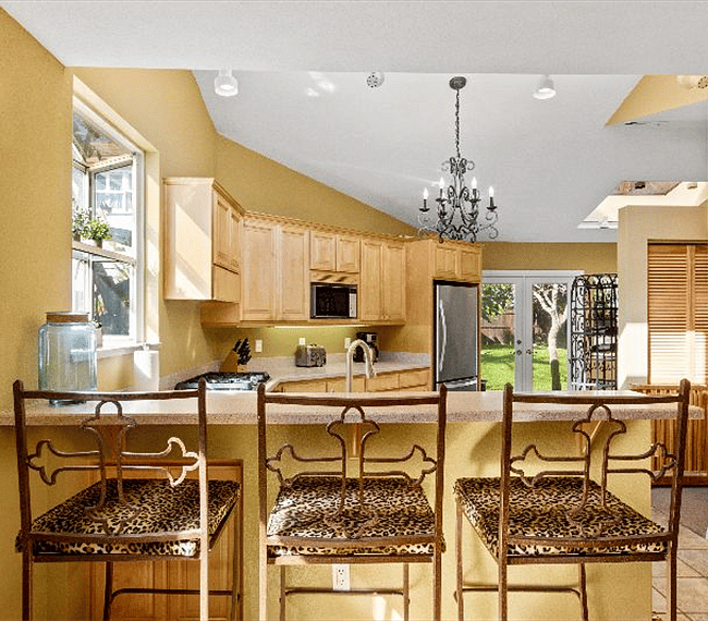 Fully equipped traditional kitchen with wooden shelves, counter bar, chairs and all essential implements included