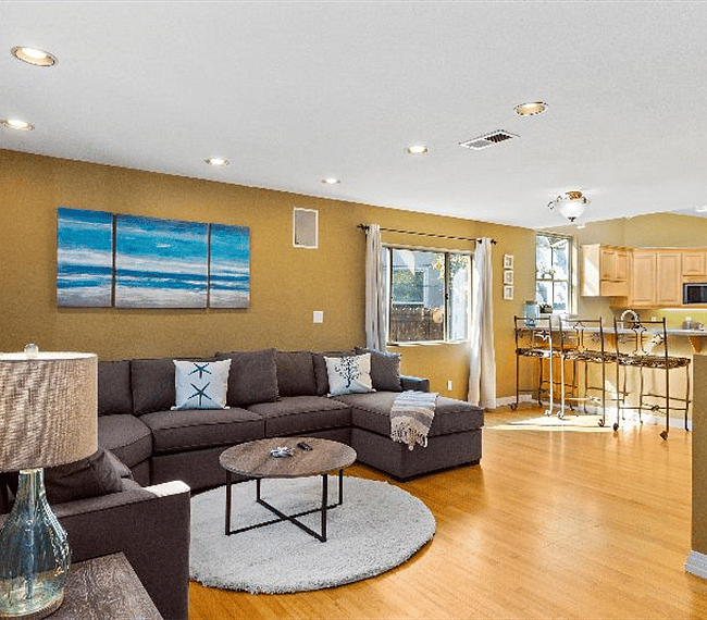 Spacious living room with sectional U-Type sofa with white carpet, lovely paintings & table