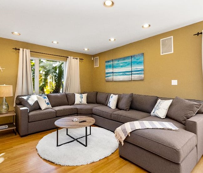 Spacious living room with sectional U-Type sofa with white carpet, lovely paintings & table