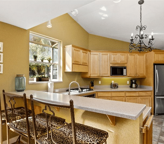 Fully equipped traditional kitchen with wooden shelves, counter bar, chairs and all essential implements included