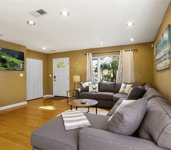 Spacious living room with sectional U-Type sofa with white carpet, lovely paintings & table