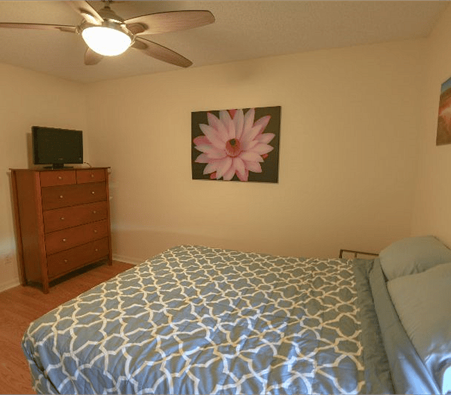 Comfortable guest bedroom furnished with dresser, LCD TV, adjustable queen bed.