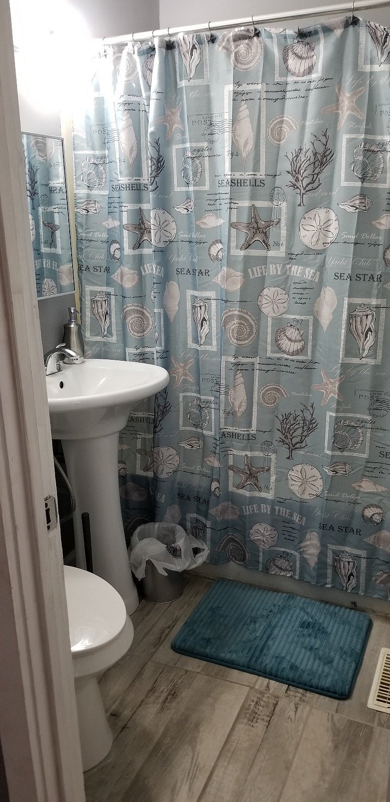 Newly renovated Bathroom with tile flooring, dual flush commode, new vanity, and glistening white tile shower with adjustable handheld shower head.