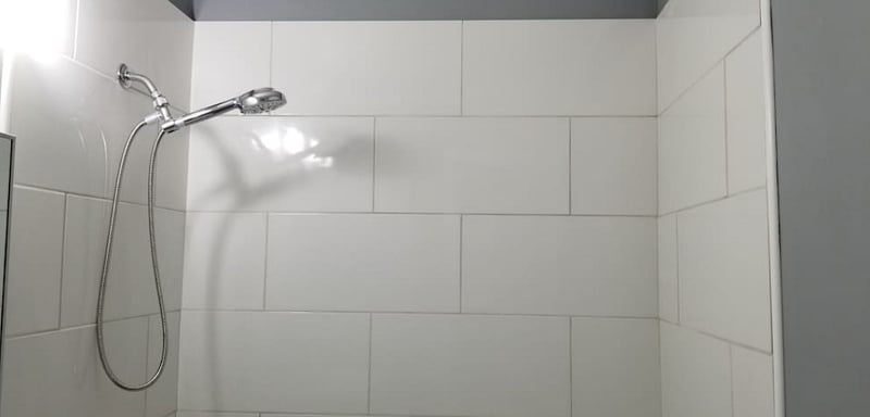 Newly renovated Bathroom with tile flooring, dual flush commode, new vanity, and glistening white tile shower with adjustable handheld shower head.