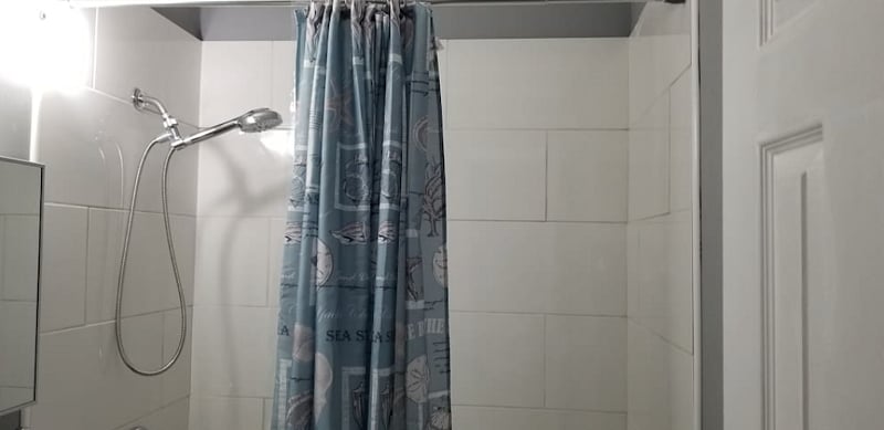 Newly renovated Bathroom with tile flooring, dual flush commode, new vanity, and glistening white tile shower with adjustable handheld shower head.