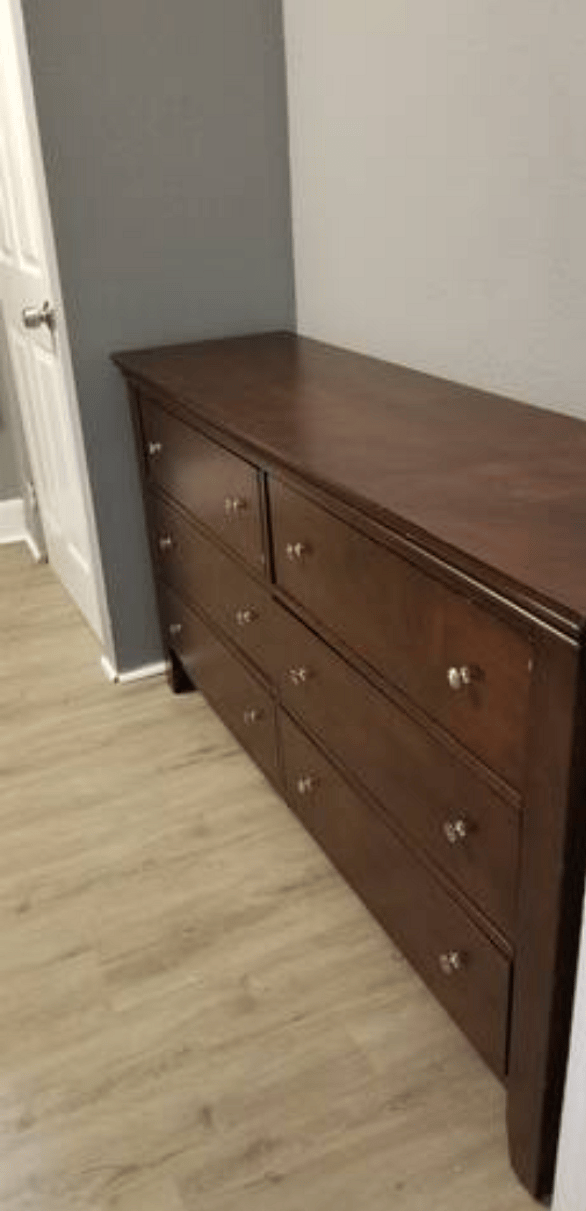 The Back Bedroom - Features (1) soft but firm Queen Bed with plush pillows, a dresser, night stand & lamp with colored smart bulb controlled by Google Assistant.