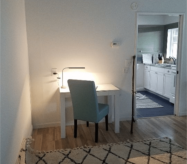 Spacious and modern living room with a traditional leather sofa, 1  addtional seat, stuffed  cushions and wide white & black carpet. Behind the living room you will be able to find a work station