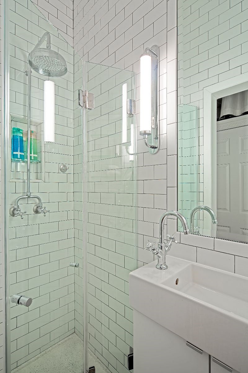 Glass enclosed shower with rainfall spout.