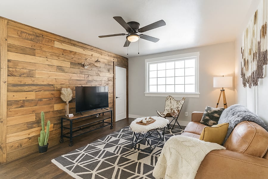 This cozy living room features a warm wood accent wall, leather sofa, and all the comforts you need for a relaxing night in.