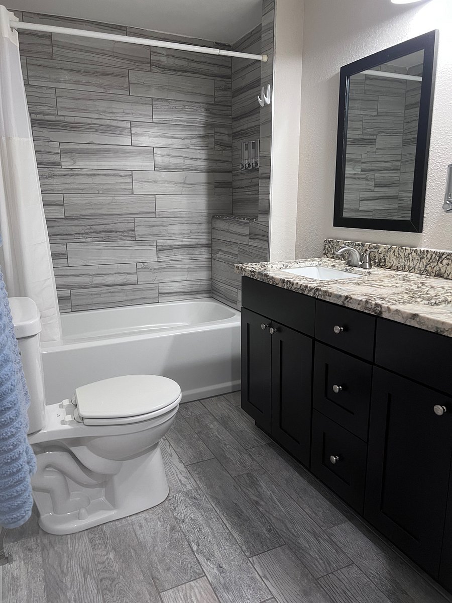 Bright full bathroom features tub/shower combination, spacious vanity, and two sinks