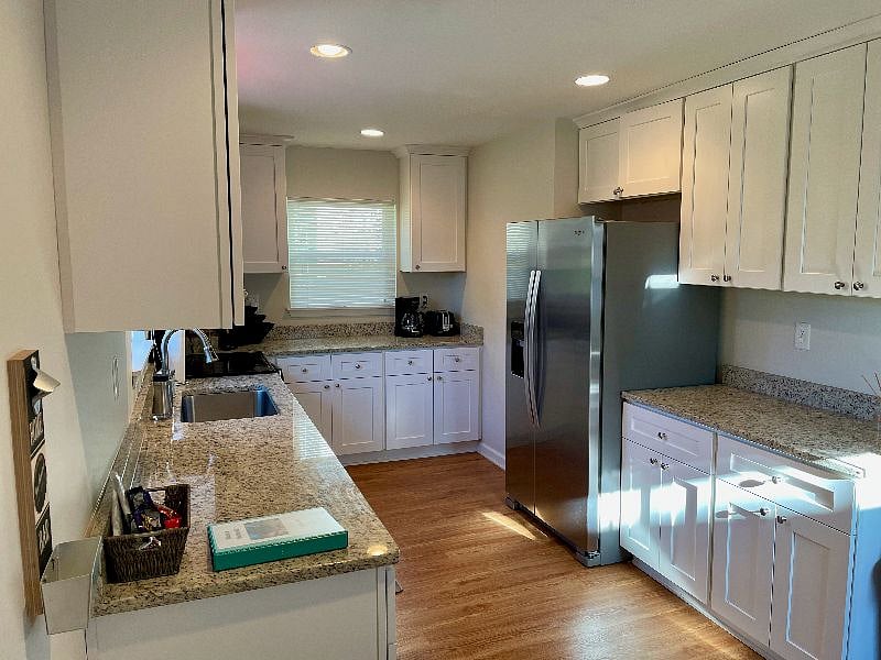 The updated kitchen features a stainless steel fridge and granite countertops.