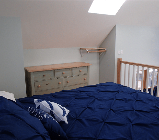 The loft includes a dresser and a small rack for clothing on hangers