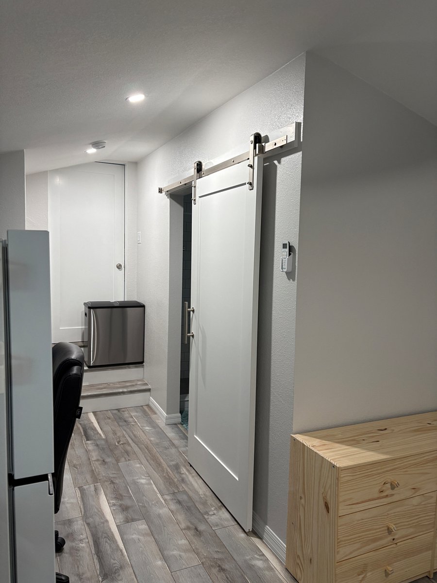 Barn door leads to the bathroom. Garbage can with recycle bin can rest on the stairs, next to the closet, with more storage. 