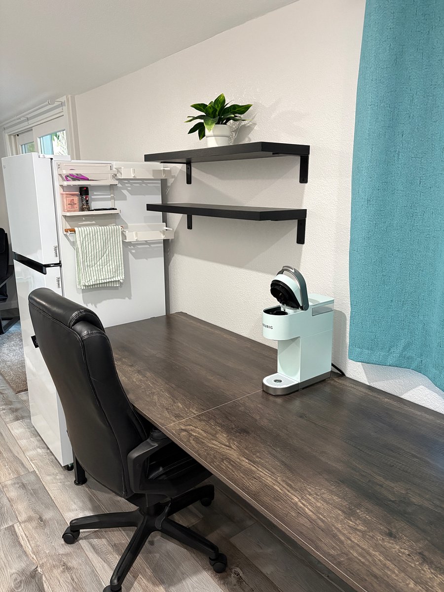 Extra long desk for eating and/or working on a computer. Keurig coffee maker. 2 floating shelves. Magnets on side of the medium sized brand new fridge to hold items and hooks to hang things.
