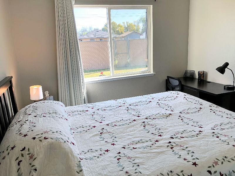 Your bedroom, with views of green grass and shady trees.