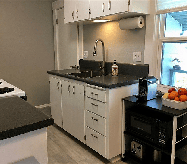 Compact but well-stocked galley kitchen with stainless sink; extra appliances (Instant Pot, etc.) available in adjacent utility room storage