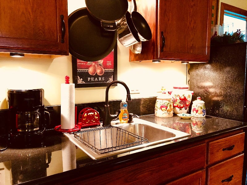 Black granite countertops, stainless steel sink with oil-rubbed bronze faucet and under-cabinet lighting create a truly functional meal prep area.