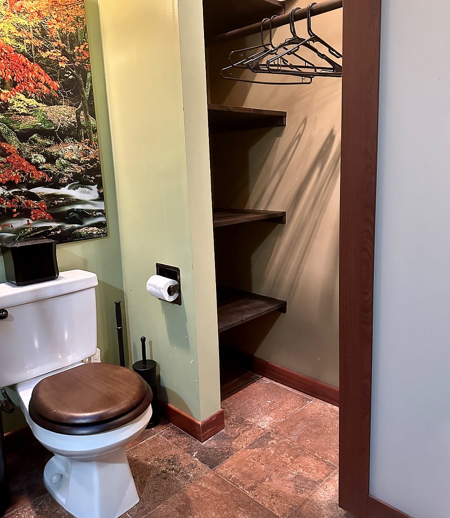 The bathroom has an ample lighted closet with sliding frosted glass doors, shelves, clothes hanging rod, hangers, iron and ironing board.