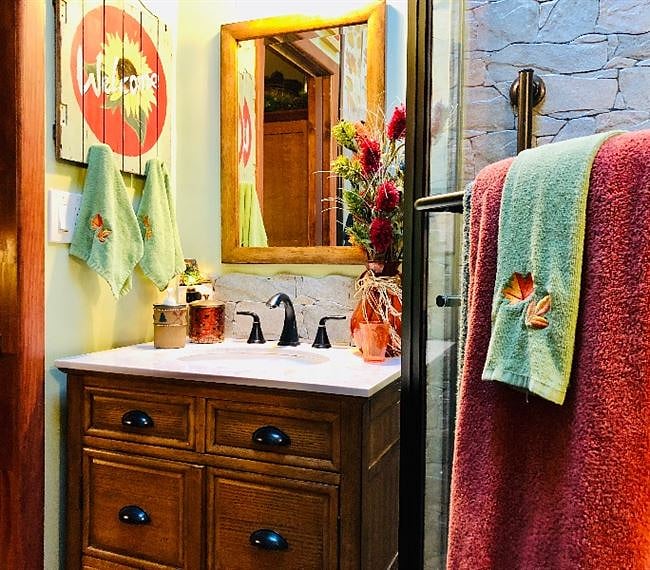 This autumnal bathroom features a vintage apothecary style vanity with under-mount porcelain sink, Carrara marble countertop and oil-rubbed bronze fixtures.