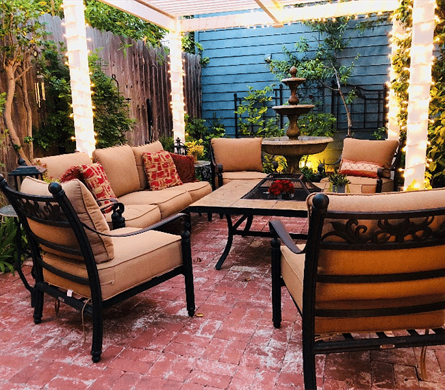 The Cabin looks out onto a relaxing patio seating area with thick cushions surrounding a fire pit table. A white lighted pergola complete the space.