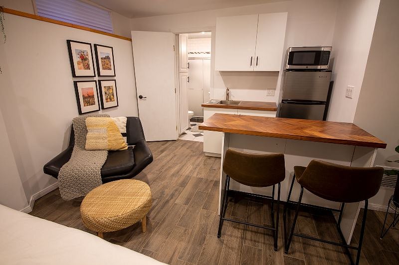 Kitchen with island, medium size fridge (with freezer) lounge chair and ottoman.