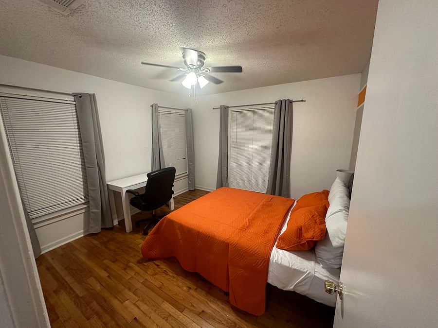 bedroom with full bed and desk and chair and blackout curtains