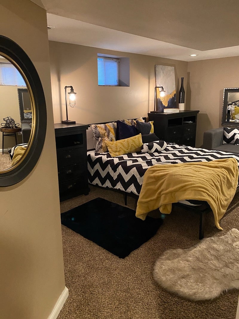 Basement bedroom with chair, two large dressors, closet and platform bed