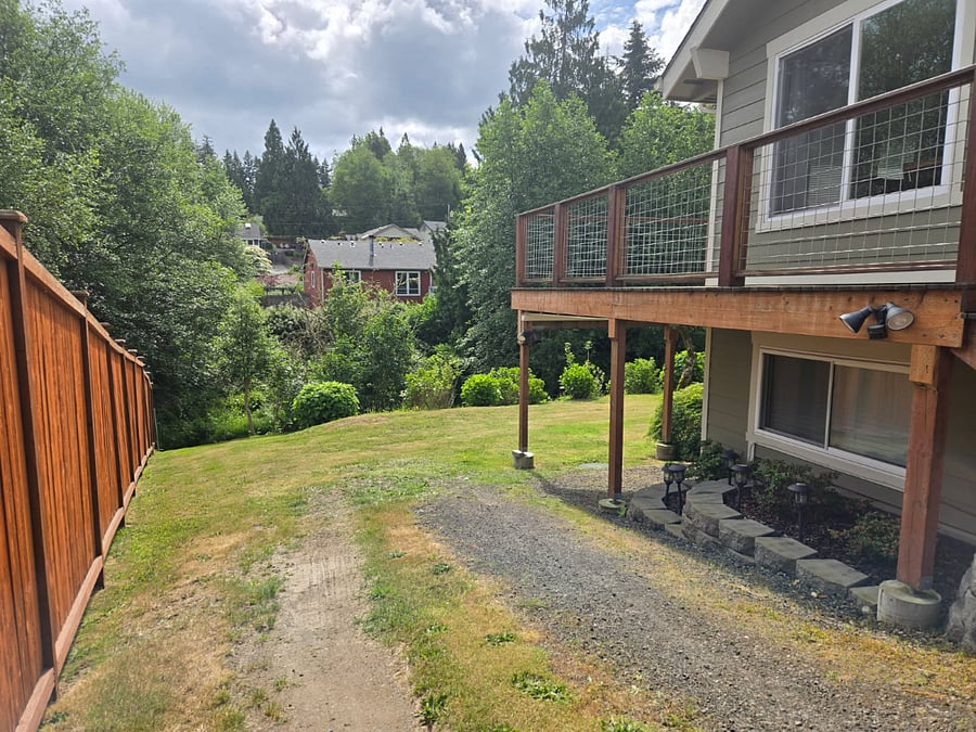 Side view of the house showing the pathway leading toward the downstairs unit access point at the rear.