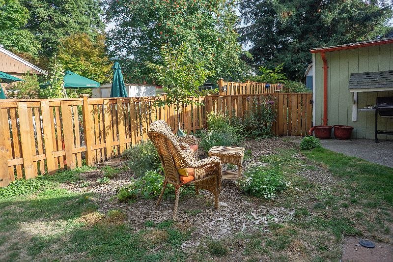 Fully fenced yard and outdoor seating, including table and chairs for patio dining.