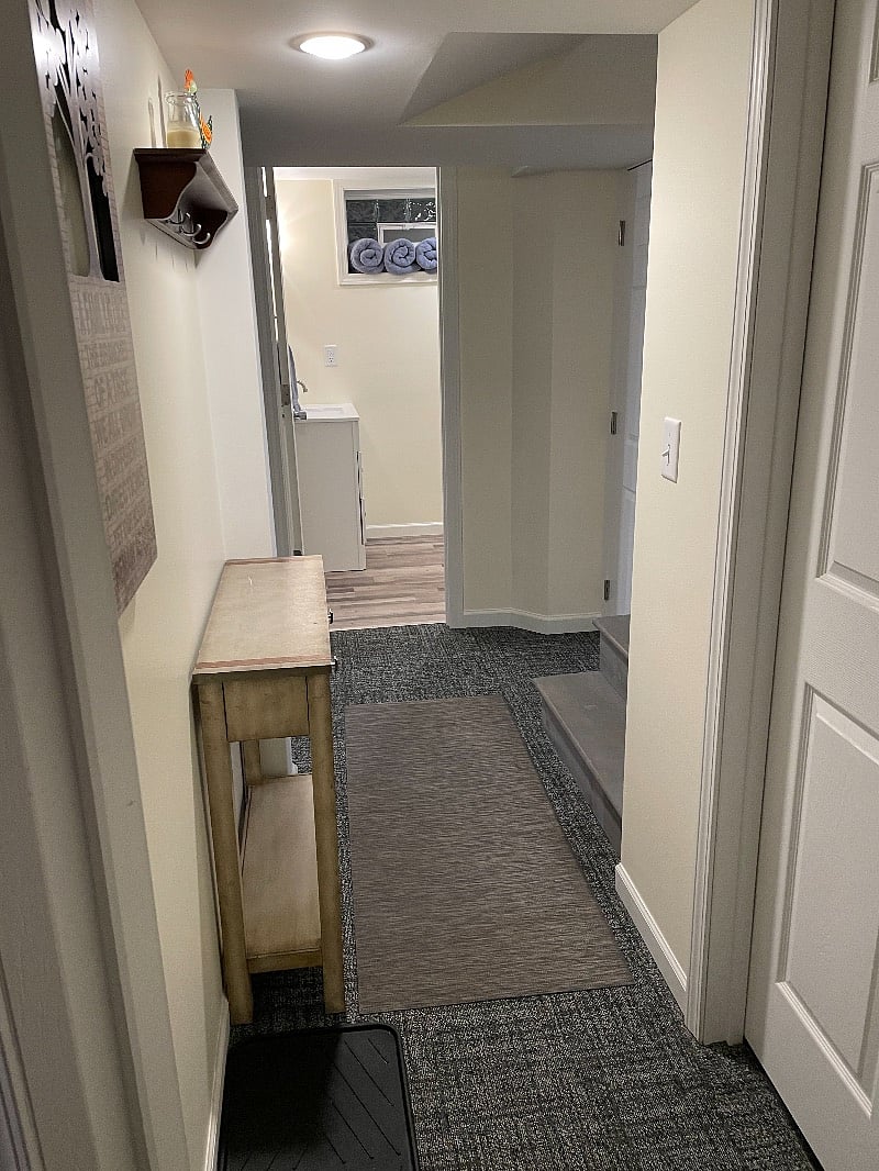 Hallway at bottom of stairs, leads to the bathroom, bedroom or laundry room.