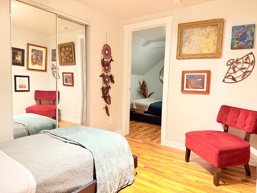 A clean, comfortable bed with fresh linens and a cozy little nook with a chair and soft accents. Simple touches that make the space feel warm and inviting.