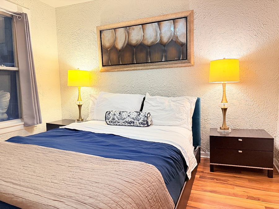 Relax in the inviting living room with a queen bed accented by two bedside lamps.
