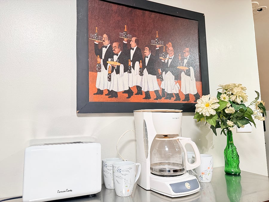 A small coffee station with a coffee maker, toaster, and mugs for your convenience.