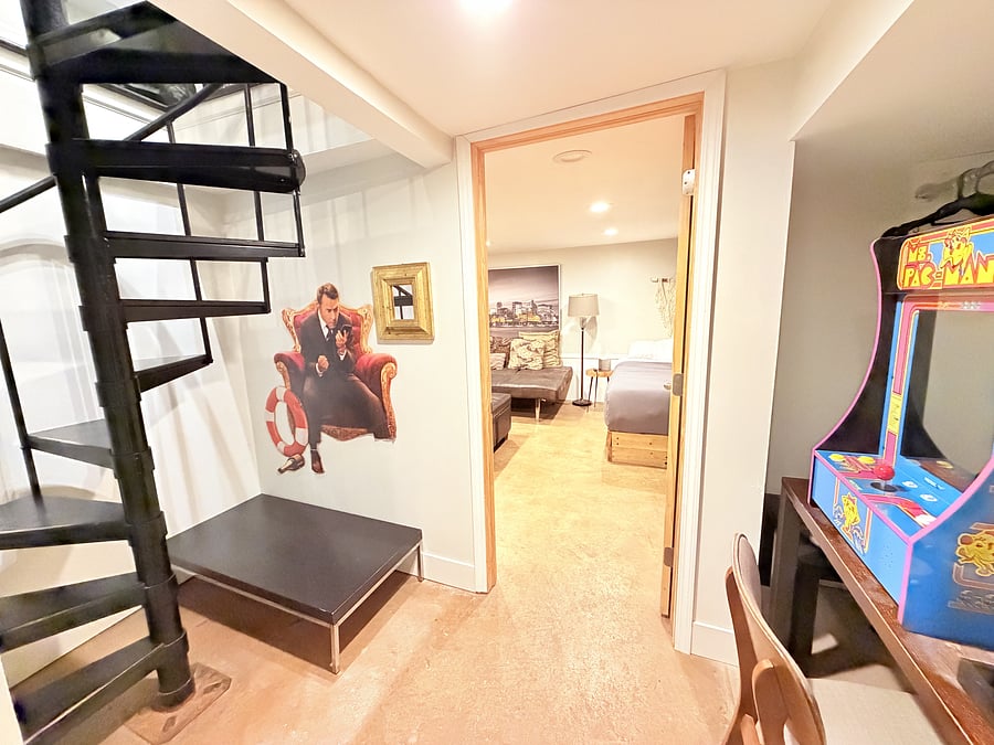 Step into a vibrant, playful space featuring a Ms. Pac-Man arcade machine, fun wall art, and a cozy bedroom just steps away. Perfect for a memorable stay filled with character, comfort, and fun.