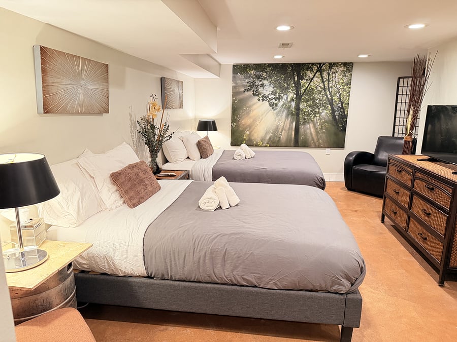 Sleep comfortably with two queen beds, fresh linens, and a flat-screen TV. A serene forest mural and a spacious dresser add a calming touch and plenty of storage for a relaxed, settled stay.