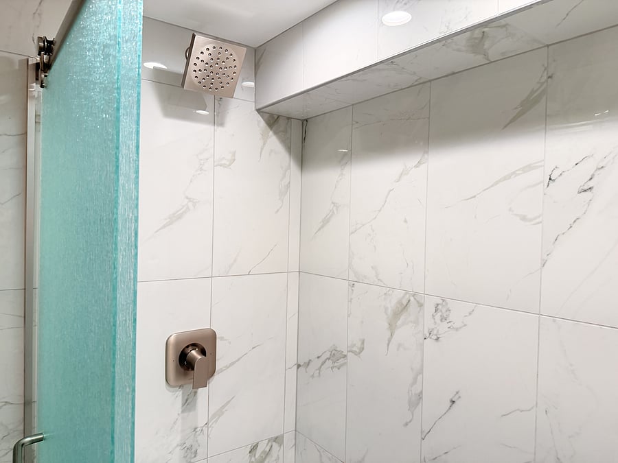 A clean, modern walk-in shower with marble-style tile, a rainfall showerhead, and built-in storage for your essentials, designed for a refreshing and comfortable experience.