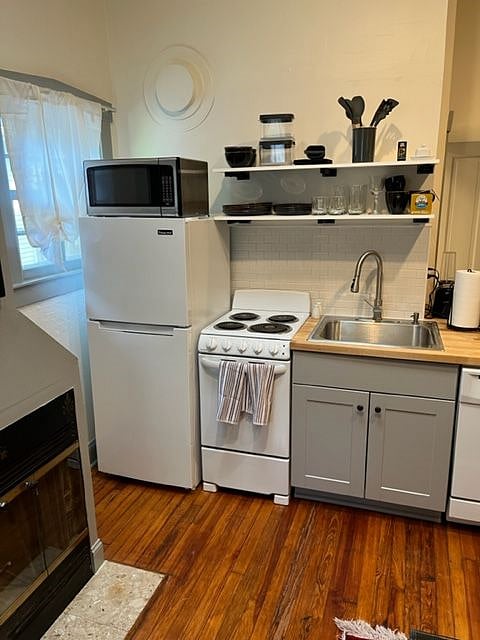Full kitchen, including dishwasher. Open shelving above sink.