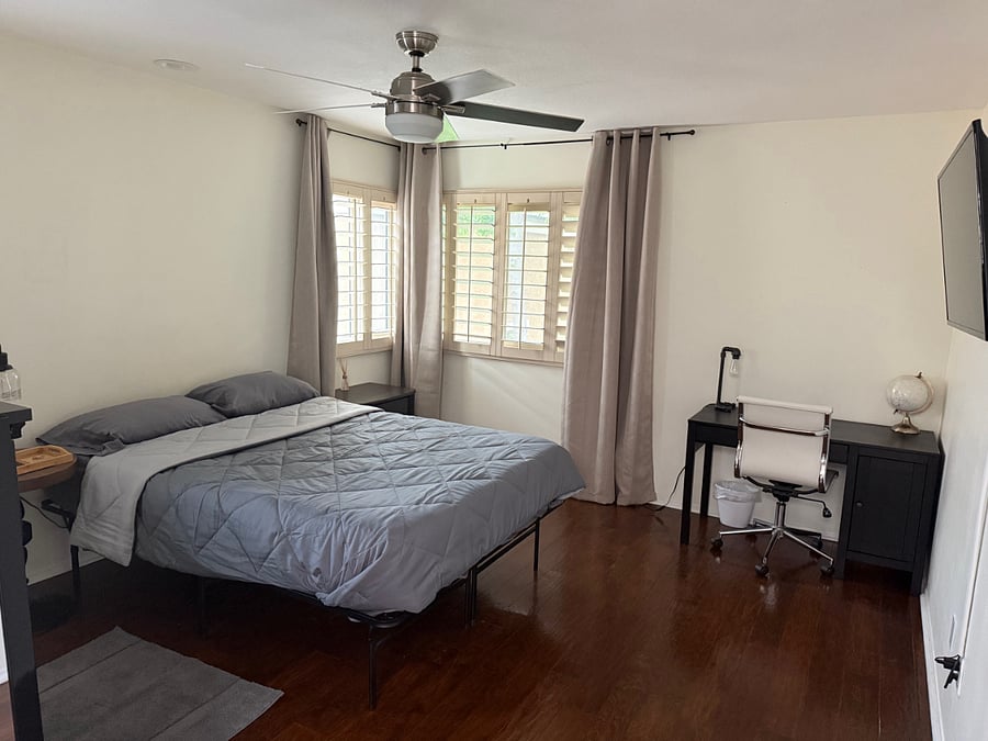 Large master bedroom with ceiling fan and desk