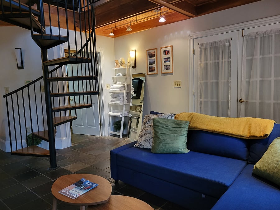 Living area, staircase to loft & bathroom entrance.