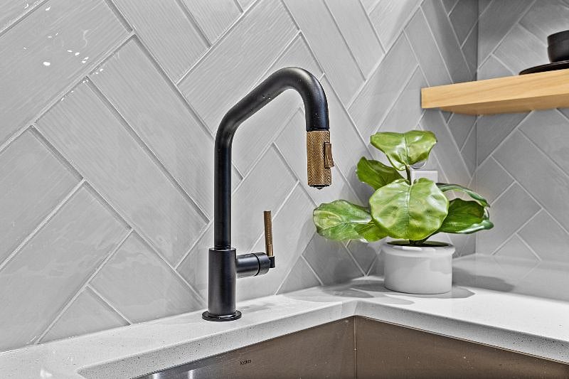 Modern faucet and sink.  Bronze piece extends as a sprayer.