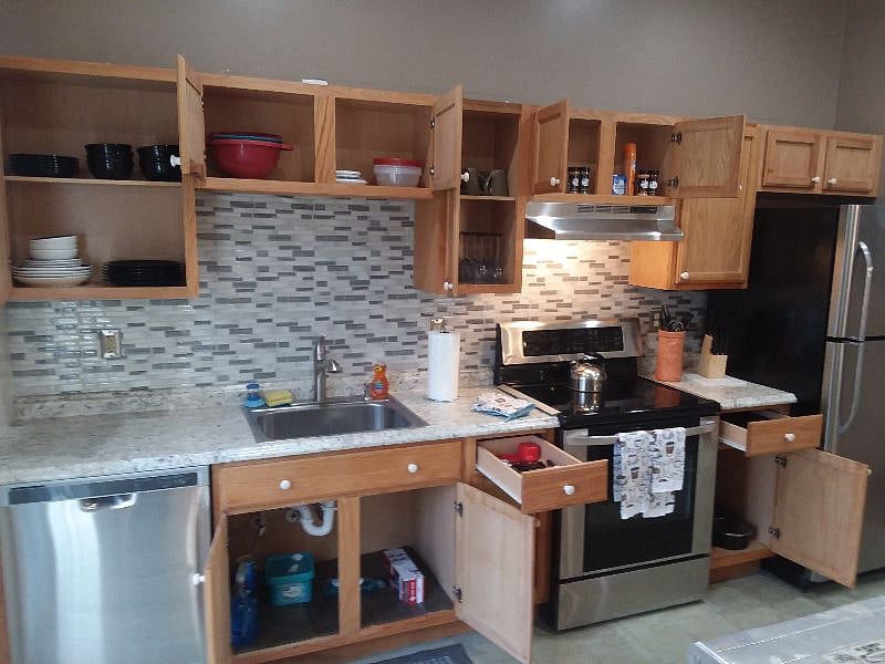 Expoded View showing ample cabinet space. Home included with plates/ cups/ coffee mugs/ wine glasses/ kitchen tools/ pots and pans/ frying pan/ knife block/ measuring cups. Stocked with spices/ sugar/ salt/ pepper