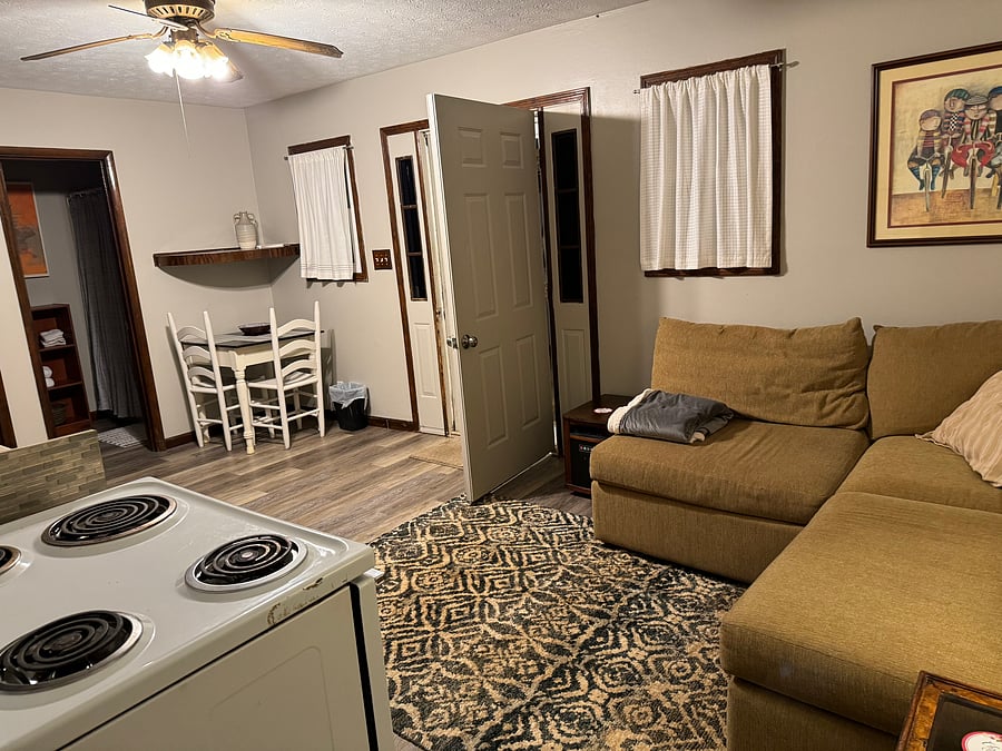 Living area, kitchen, stove, microwave, refrigerator and table/ chairs for workspace or dining.