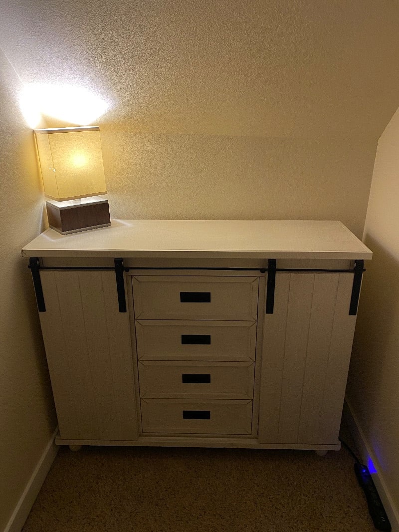 This brand new dresser is solid wood and adorable! It has barn doors that slide open and have 2 shelves on each side with a black basket for storage on each shelf. The center area have 4 separate drawers for clothing and storage.