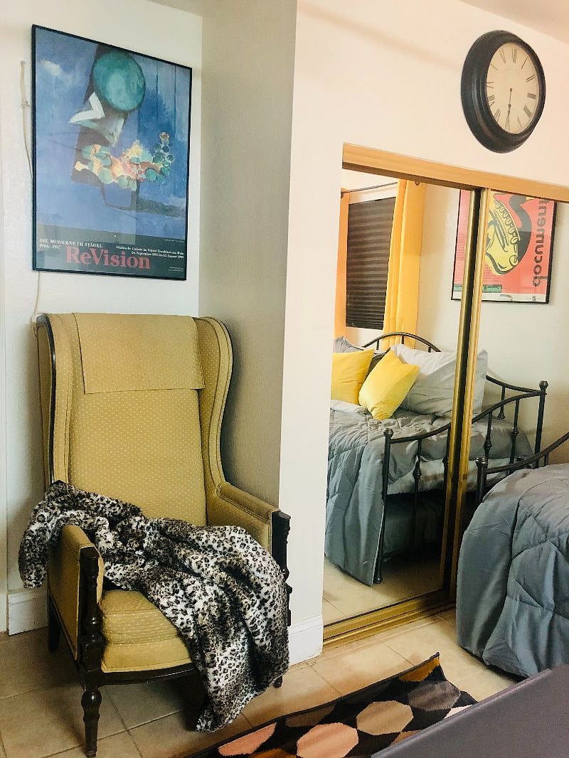 Wing back chair with throw blanket. Full closet with sliding mirrored doors. Large enough for a person to walk into. Walls are decorated with framed museum pictures from Germany and France.