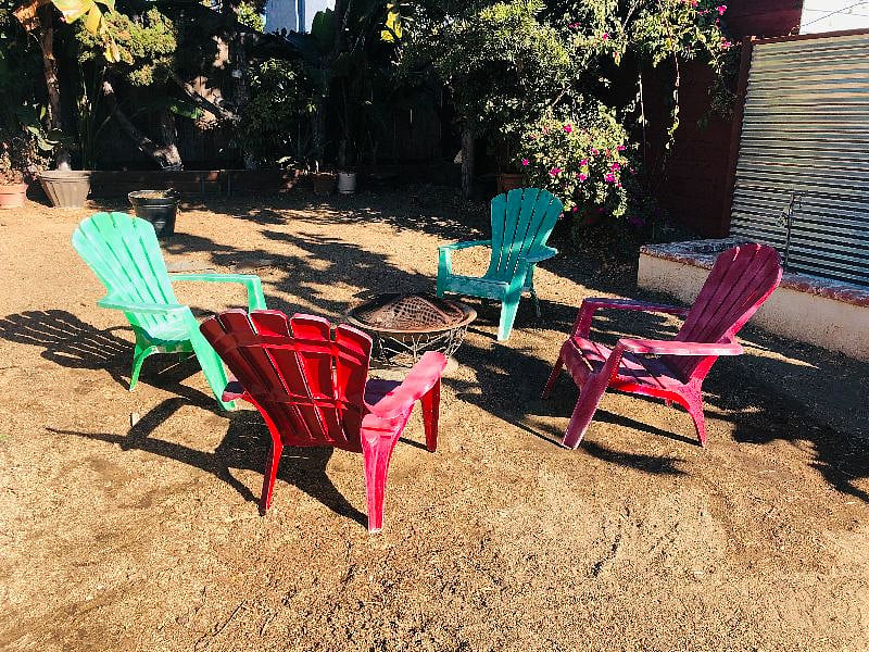 Large yard with firepit and adirondack chairs.