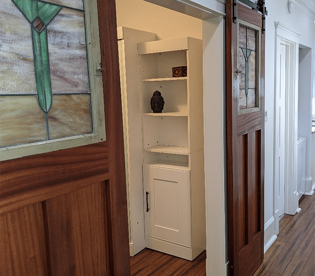 Custom barn doors with 1920's salvaged glass panels open to reveal office/bedroom.