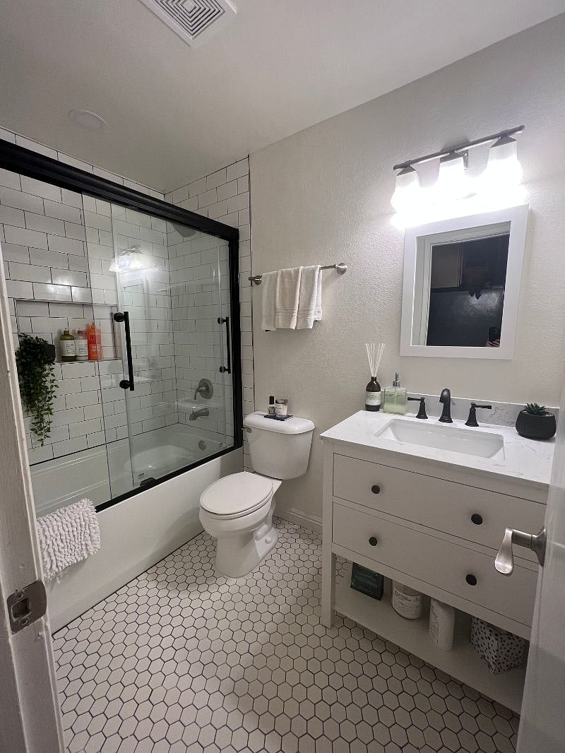 This full and newly remodeled guest bathroom features a bathtub/shower with subway tile, gorgeous honeycomb floor and marbeled vanity with abundant storage space.